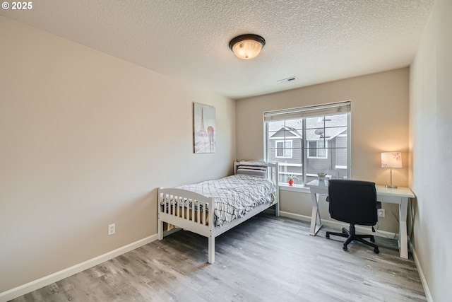 bedroom with hardwood / wood-style flooring and a textured ceiling