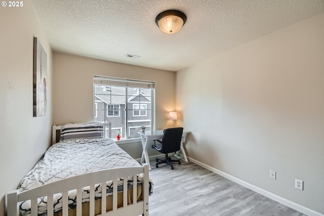 bedroom with light wood-type flooring and a textured ceiling