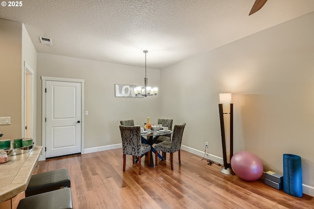 dining room with hardwood / wood-style flooring, a textured ceiling, and a notable chandelier