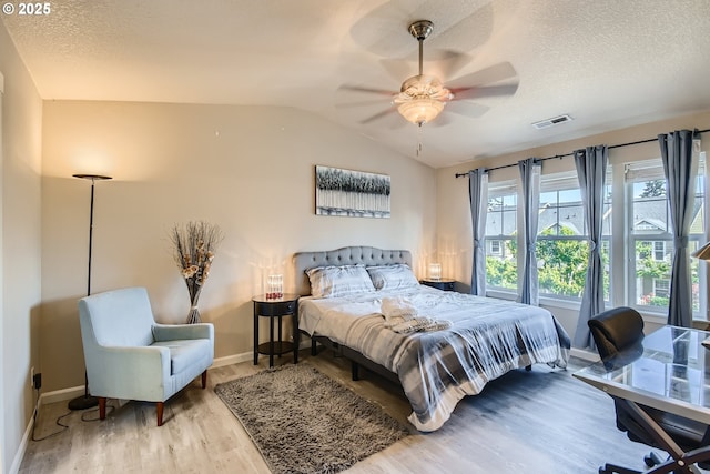 bedroom featuring vaulted ceiling, ceiling fan, light hardwood / wood-style floors, and a textured ceiling