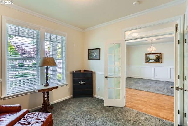 living area with french doors, crown molding, a chandelier, carpet, and wood finished floors