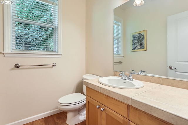 half bath with healthy amount of natural light, vanity, and wood finished floors