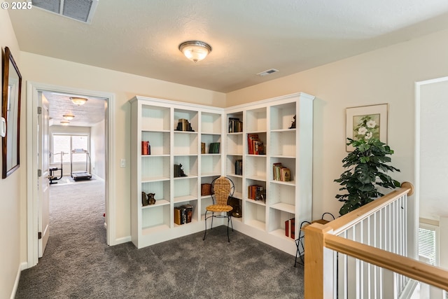 living area featuring dark colored carpet and an upstairs landing