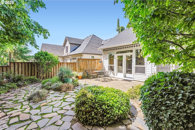 back of property with fence, a patio, and a shingled roof