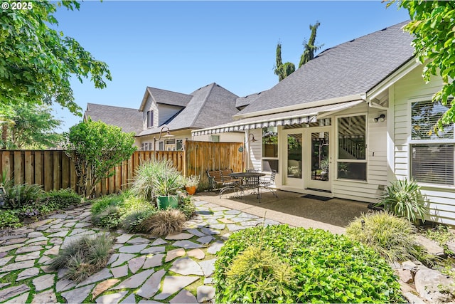 rear view of property featuring fence, a patio, and a shingled roof