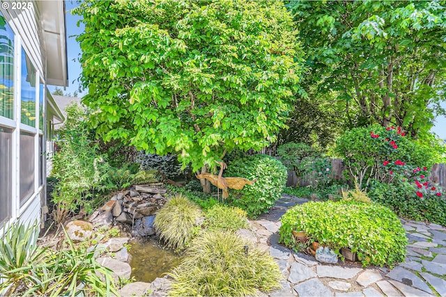 view of yard featuring fence and a garden pond