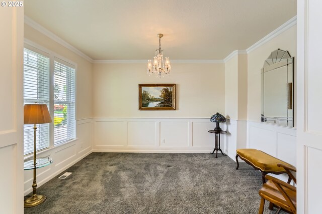 unfurnished room with plenty of natural light, a chandelier, dark colored carpet, a wainscoted wall, and ornamental molding