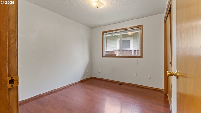 unfurnished bedroom featuring wood finished floors, a textured ceiling, baseboards, and a closet