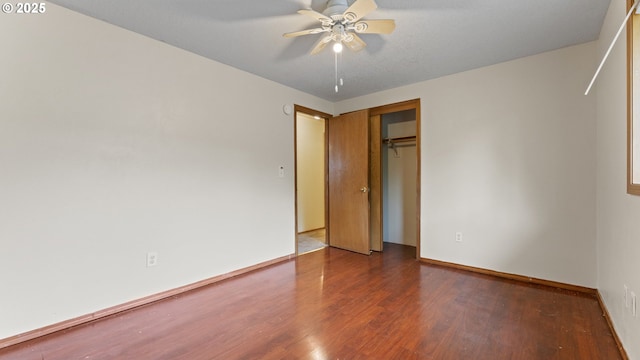 unfurnished bedroom featuring wood finished floors, a closet, baseboards, and a ceiling fan