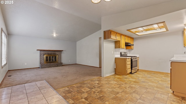 kitchen featuring gas range, light carpet, light countertops, under cabinet range hood, and vaulted ceiling