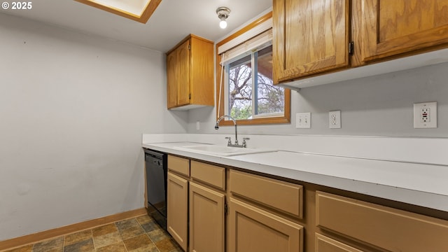 kitchen featuring a sink, black dishwasher, baseboards, stone finish floors, and light countertops