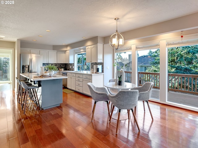 dining area with sink, hardwood / wood-style floors, a notable chandelier, and a textured ceiling