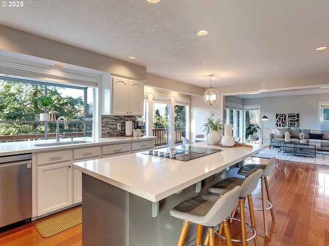 kitchen with pendant lighting, white cabinetry, dishwasher, sink, and black electric stovetop