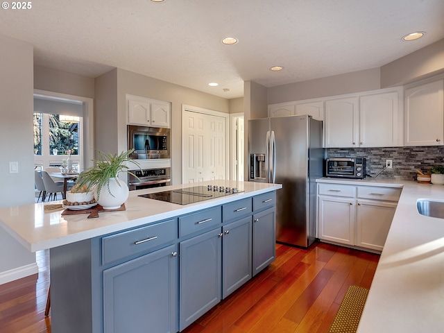 kitchen featuring stainless steel appliances, white cabinetry, tasteful backsplash, and dark hardwood / wood-style flooring