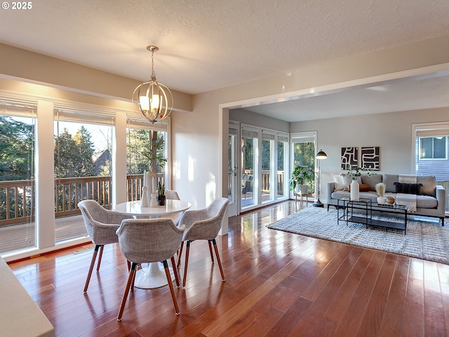 dining area featuring wood-type flooring, a chandelier, and a textured ceiling