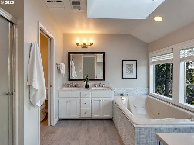 bathroom with toilet, vaulted ceiling, vanity, tiled tub, and hardwood / wood-style flooring