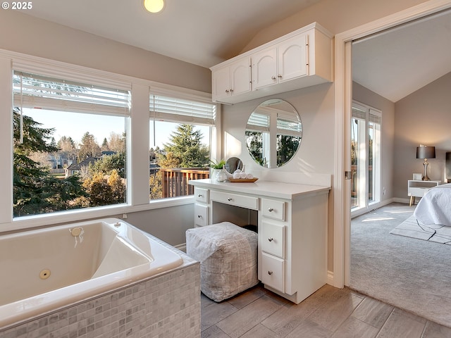 bathroom featuring vaulted ceiling, hardwood / wood-style floors, and tiled tub