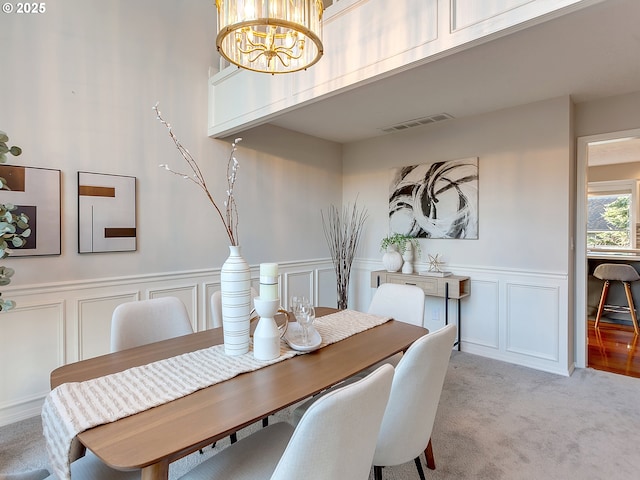 dining room featuring light carpet and a chandelier