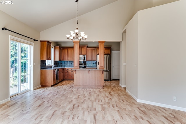 kitchen featuring brown cabinets, decorative light fixtures, backsplash, stainless steel appliances, and a breakfast bar area