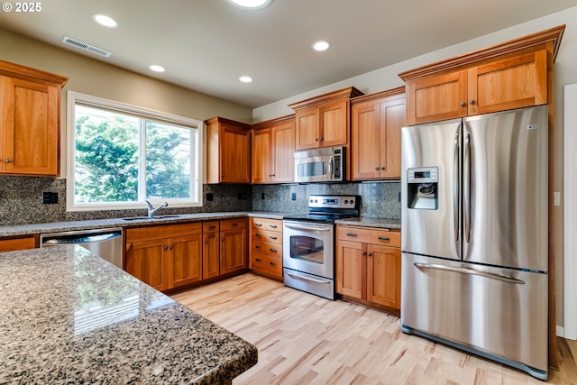 kitchen featuring visible vents, appliances with stainless steel finishes, light stone countertops, and a sink