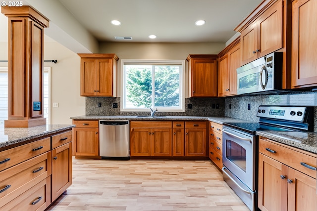 kitchen featuring visible vents, backsplash, dark stone countertops, appliances with stainless steel finishes, and a sink