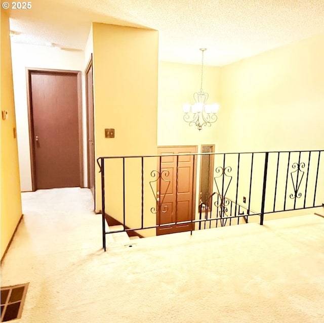14807 NE Siskiyou Ct, Portland, OR 97230 - hallway featuring an upstairs landing, carpet, a chandelier, and a textured ceiling