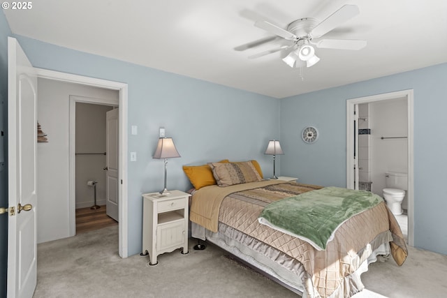 bedroom featuring light carpet, ensuite bath, and a ceiling fan