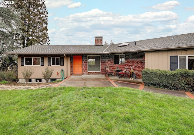 ranch-style house with brick siding, a patio, a chimney, and a front lawn