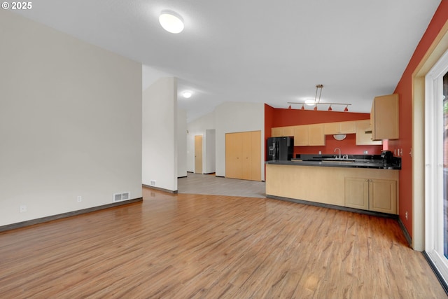 815 Bobolink Ave, Eugene, OR 97404 - kitchen with black fridge, dark countertops, light wood finished floors, a sink, and a peninsula