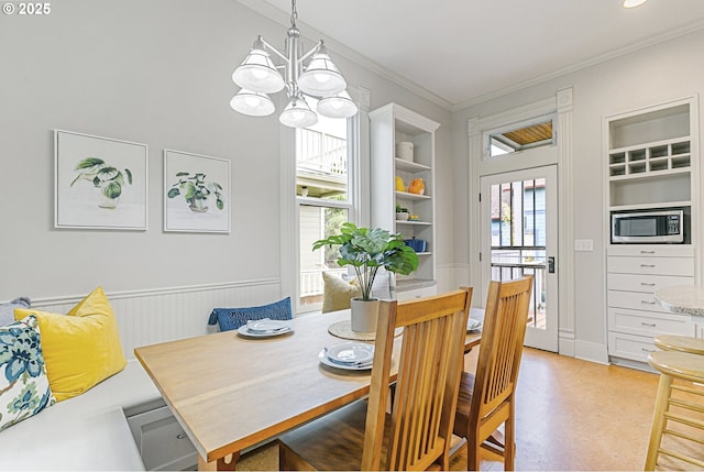 2153 NE Rodney Ave, Portland, OR 97212 - dining space with healthy amount of natural light, a chandelier, crown molding, a wainscoted wall, and built in features