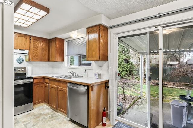 kitchen featuring a sink, tasteful backsplash, stainless steel appliances, light countertops, and extractor fan