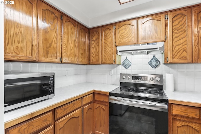 kitchen featuring brown cabinetry, appliances with stainless steel finishes, and under cabinet range hood