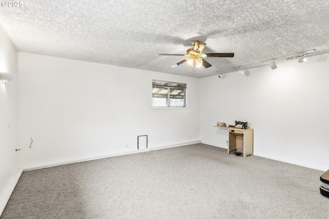 carpeted spare room with track lighting, a ceiling fan, baseboards, and a textured ceiling