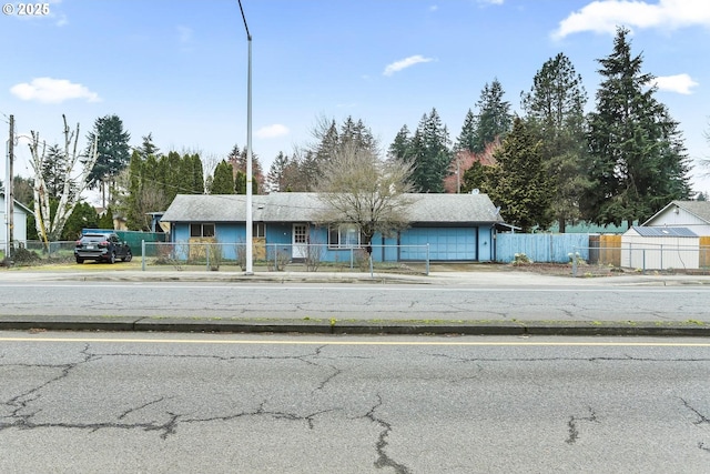 view of front facade with driveway, a garage, and a fenced front yard