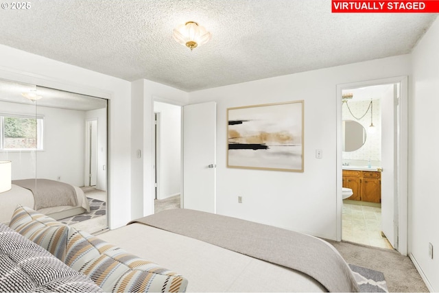 bedroom with ensuite bath, light colored carpet, a textured ceiling, and a closet