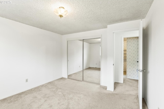 unfurnished bedroom featuring a closet, light colored carpet, and a textured ceiling