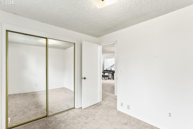 unfurnished bedroom featuring a closet, carpet, and a textured ceiling