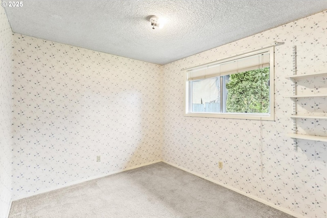 unfurnished room with carpet floors, a textured ceiling, and wallpapered walls