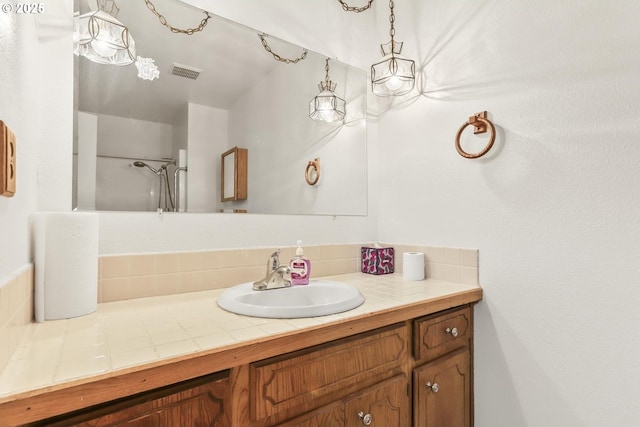 bathroom featuring visible vents, vanity, and walk in shower