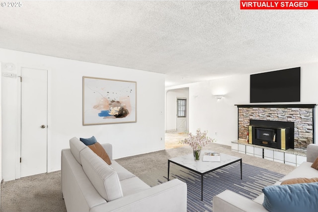 carpeted living room featuring a stone fireplace and a textured ceiling