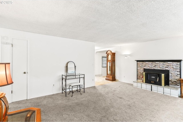 carpeted living room featuring a fireplace and a textured ceiling