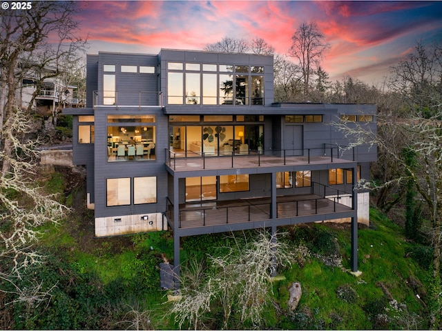 back house at dusk featuring a balcony