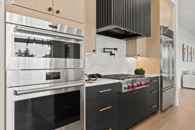 kitchen with tasteful backsplash, appliances with stainless steel finishes, and light hardwood / wood-style flooring