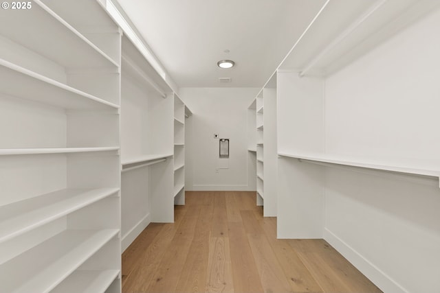 walk in closet with light hardwood / wood-style floors