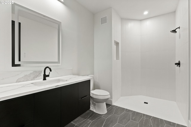 bathroom featuring tiled shower, vanity, and toilet