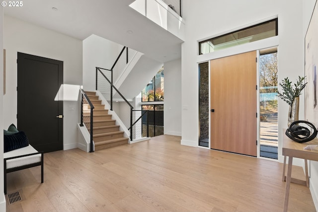 entryway featuring a towering ceiling and light wood-type flooring