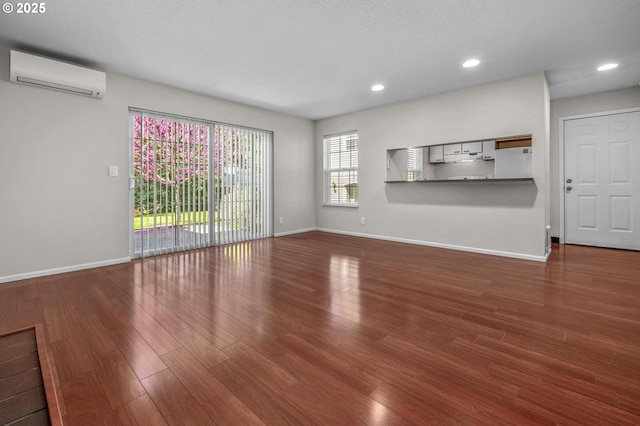8540 SW Curry Dr Unit D, Wilsonville, OR 97070 - unfurnished living room featuring wood finished floors, a wall mounted air conditioner, recessed lighting, and baseboards