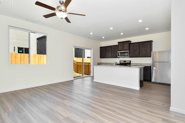 kitchen with a center island with sink, ceiling fan, stainless steel appliances, and light hardwood / wood-style flooring