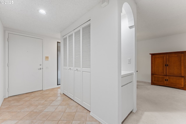 hallway featuring a textured ceiling and light tile patterned flooring