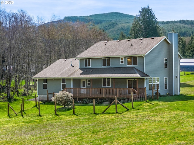 92041 Carmen Creek Rd, Astoria, OR 97103 - back of property with a chimney, a yard, a wooded view, and a deck with mountain view